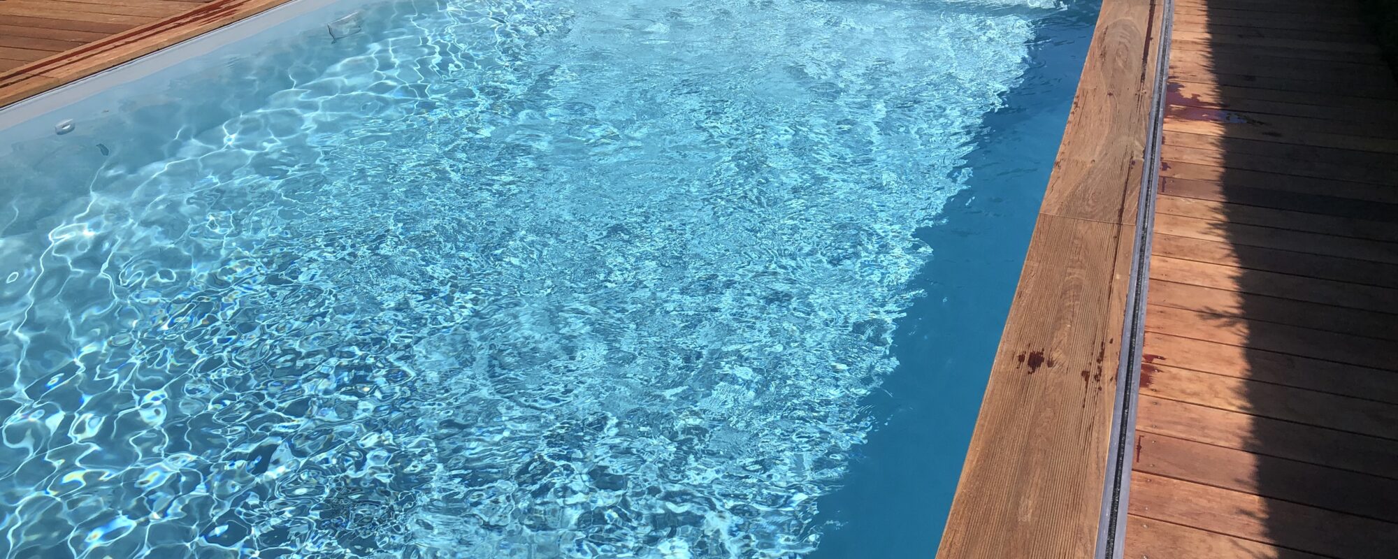 Piscine rectangulaire avec abri plat et rangement sous la terrasse, plage et lagon grès cérame