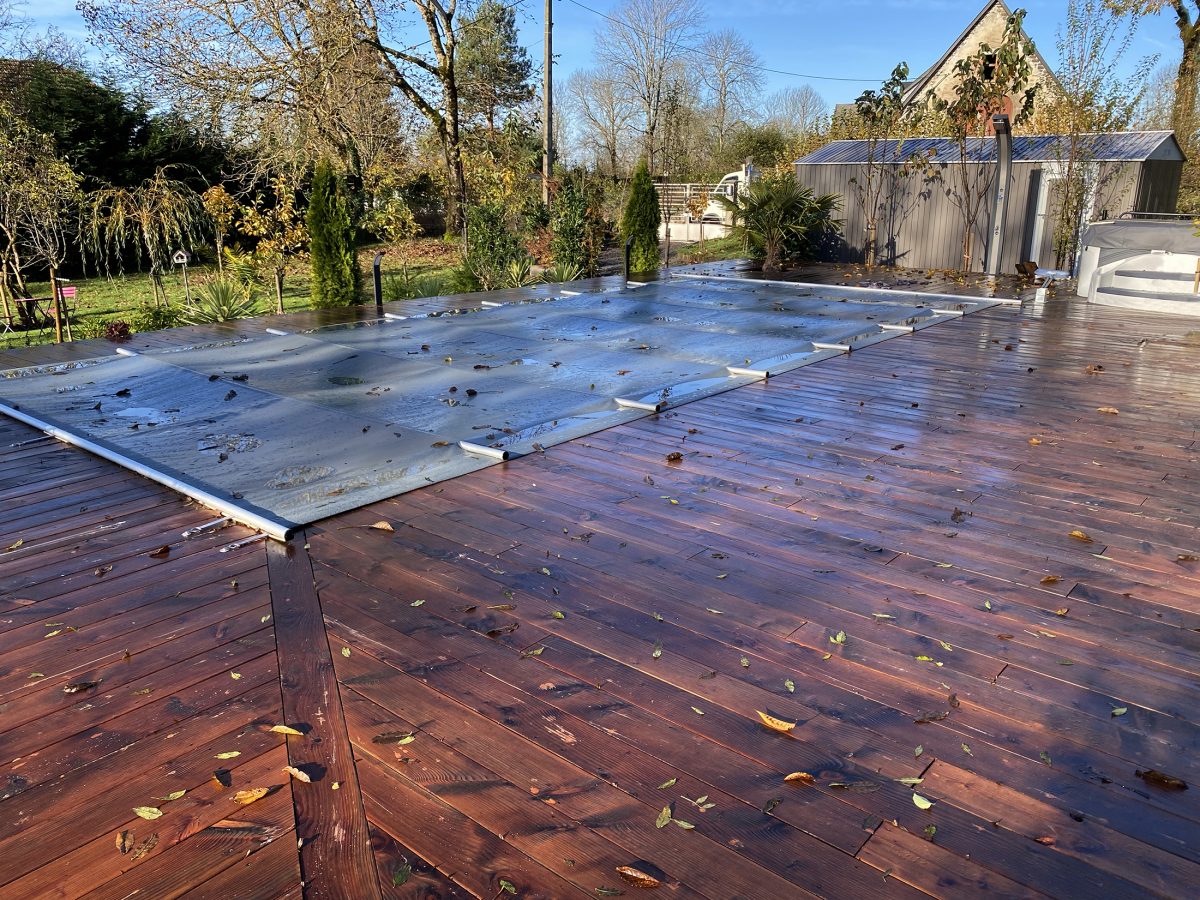 Piscine avec couverture à barre et plage en bois - Catusse Piscines & Spas