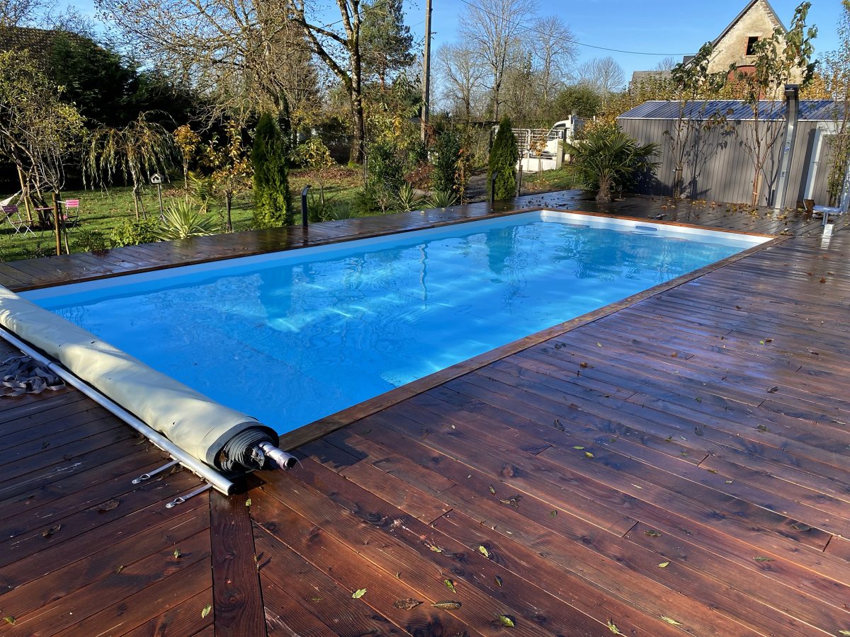 Piscine avec couverture à barre et plage en bois - Catusse Piscines & Spas